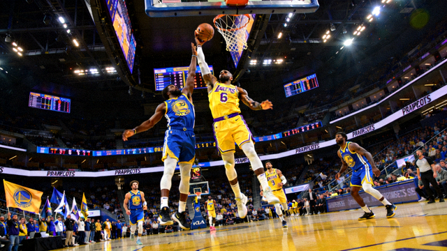 NBA季后赛篮球比赛直播画面，湖人队黄色球衣对阵勇士队蓝色球衣，球馆内灯光璀璨